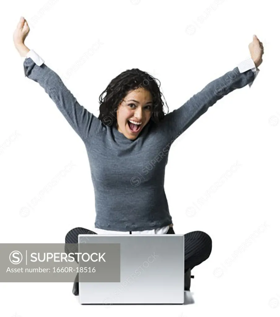 Woman sitting cross legged with laptop and arms up