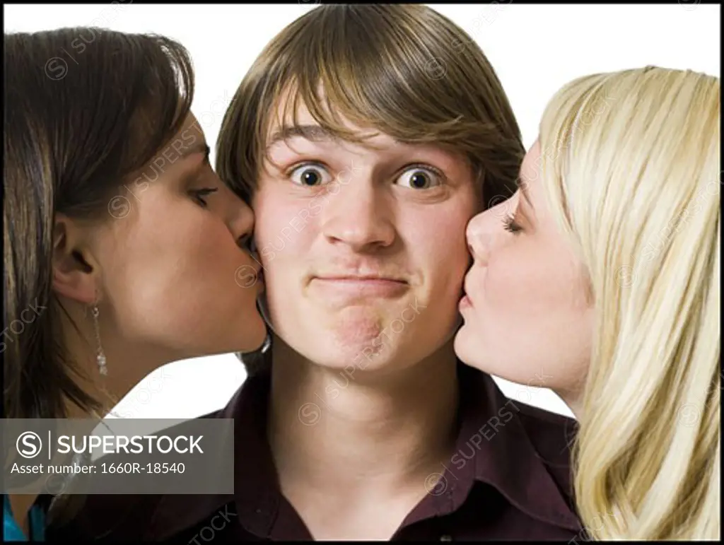 Two girls kissing boy on cheeks