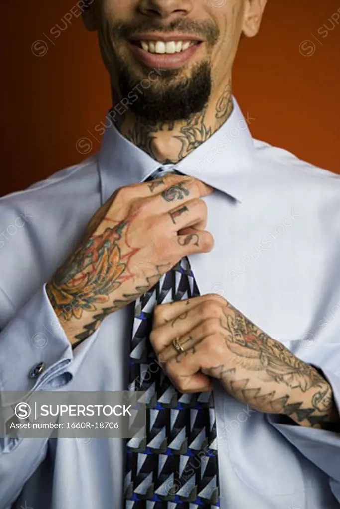 Man with tattoos in shirt and tie smiling