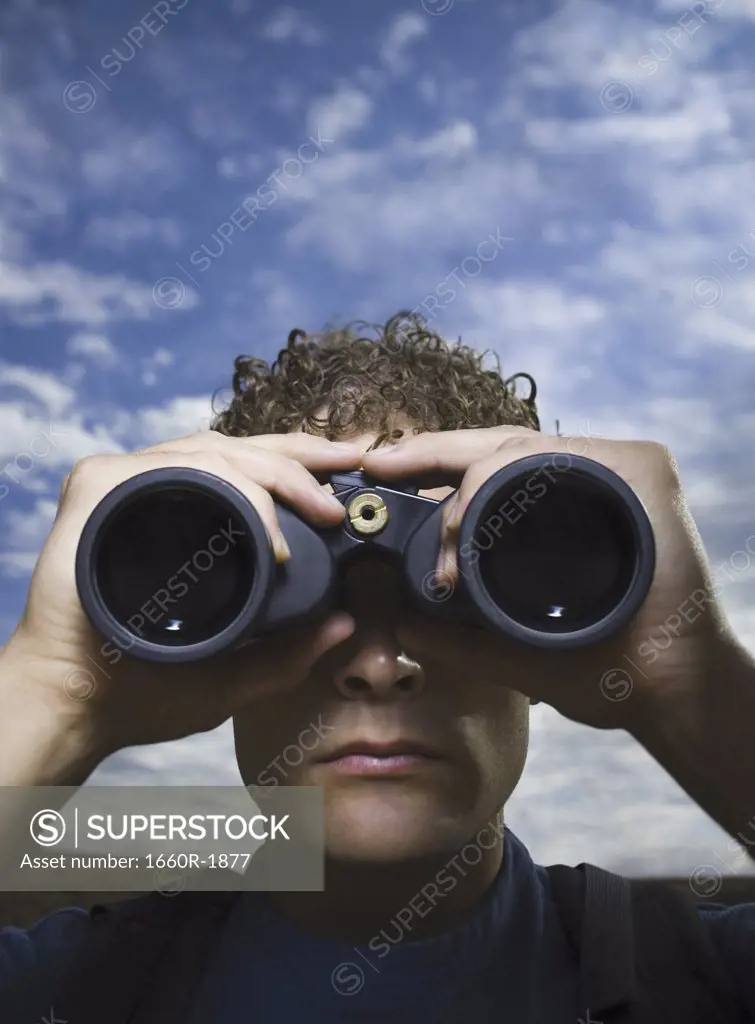 Close-up of a young man looking through binoculars