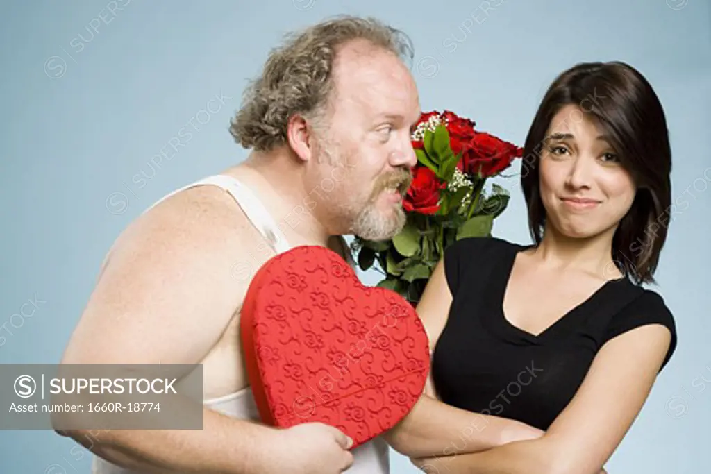 Disheveled man with heart box and roses with disinterested woman