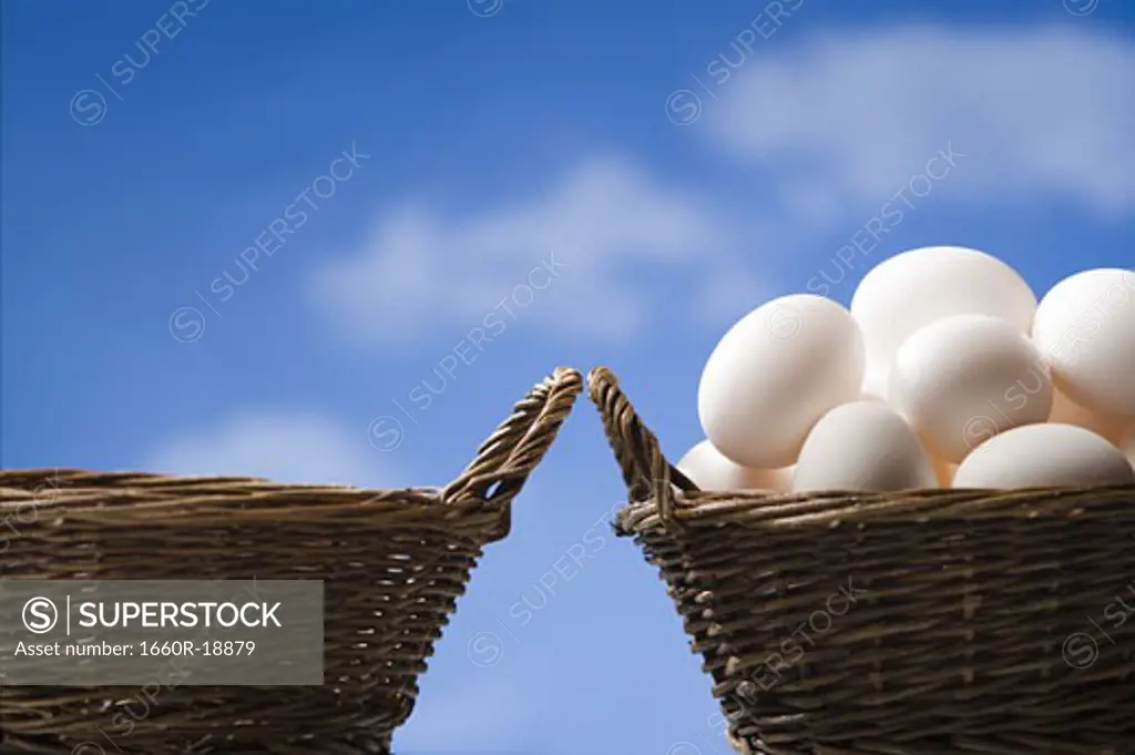 One empty basket and one basket filled with eggs outdoors with blue sky