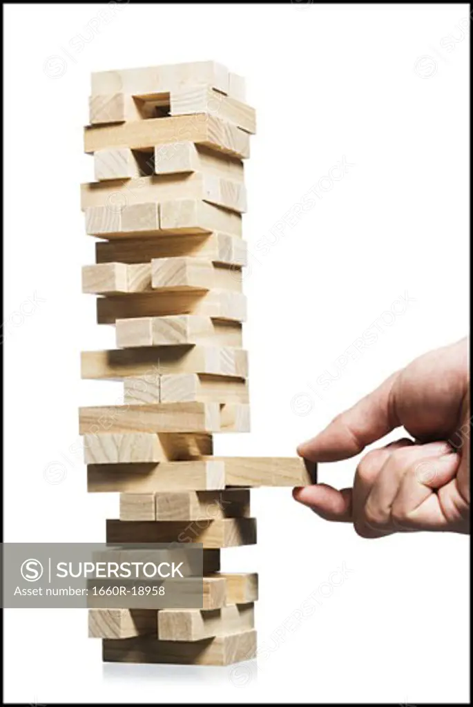 Hand removing block from stack of wooden blocks