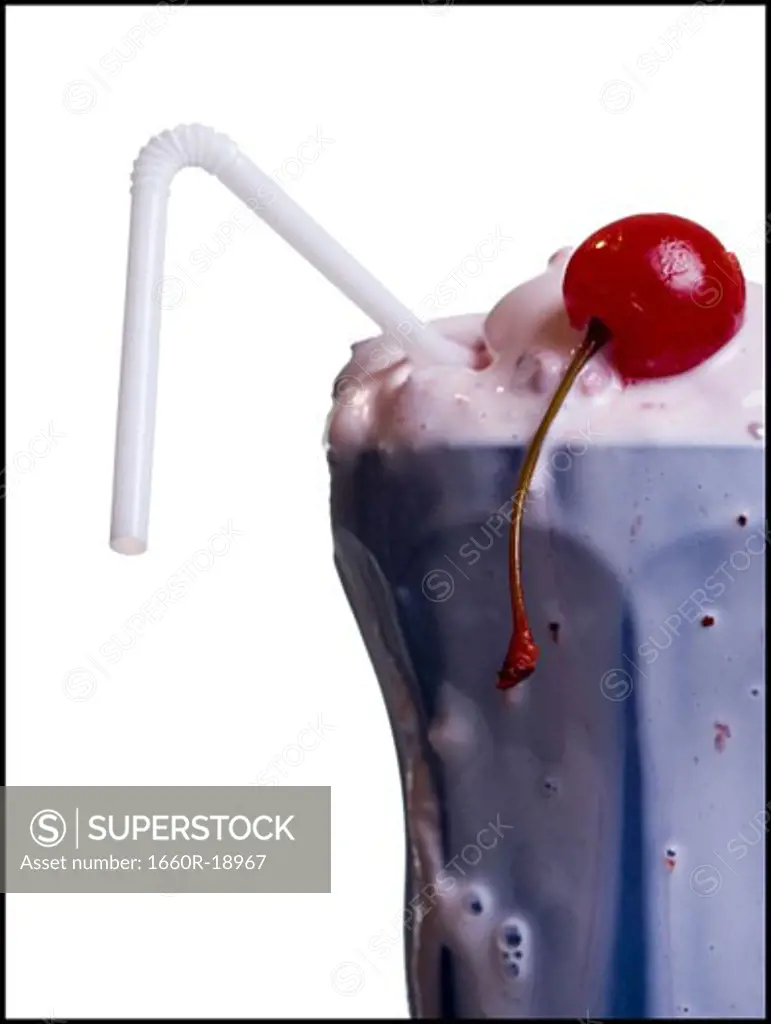 Close-up of melting milkshake with straw and maraschino cherry