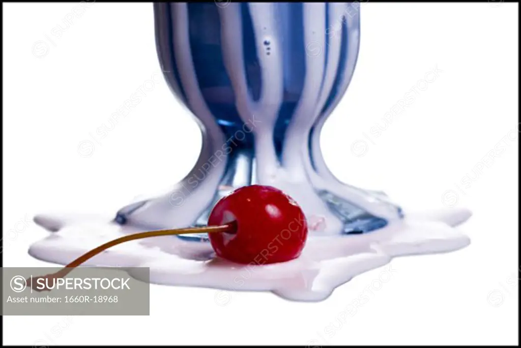 Close-up of base of melted milkshake with maraschino cherry