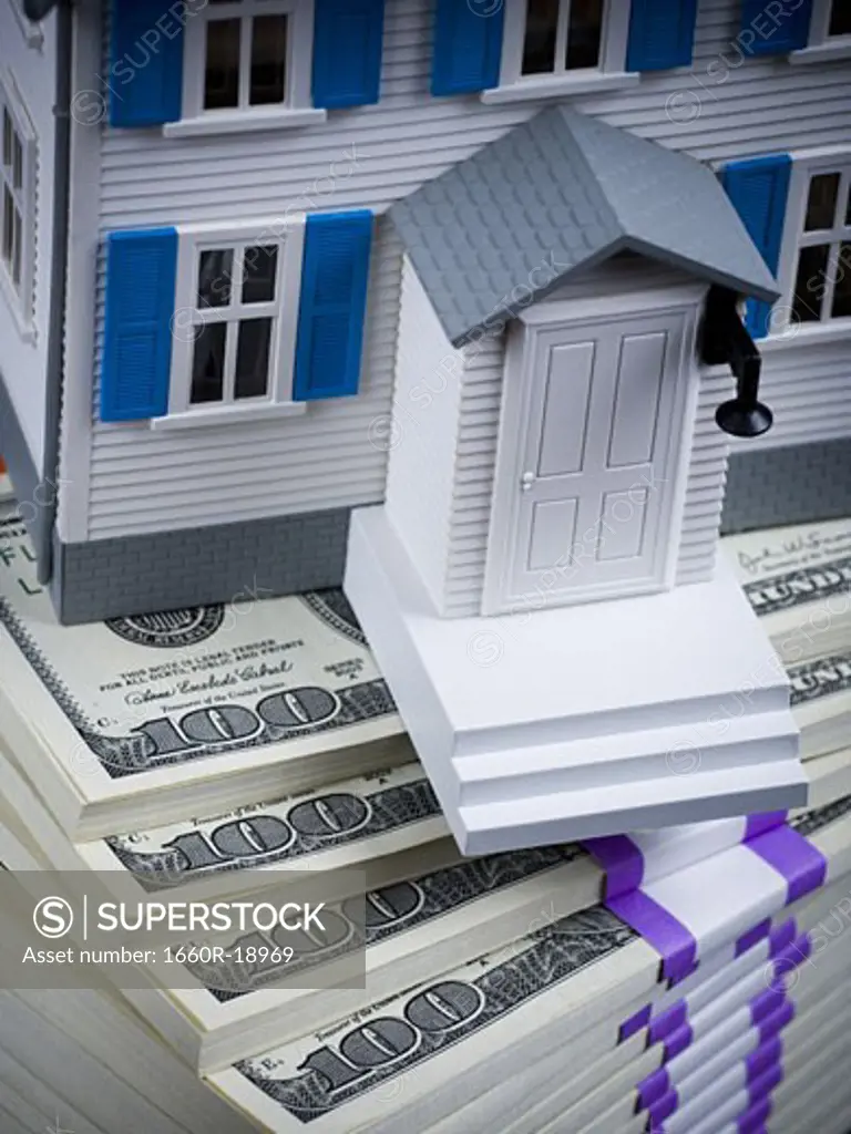 Toy house on stack of hundred dollar bills
