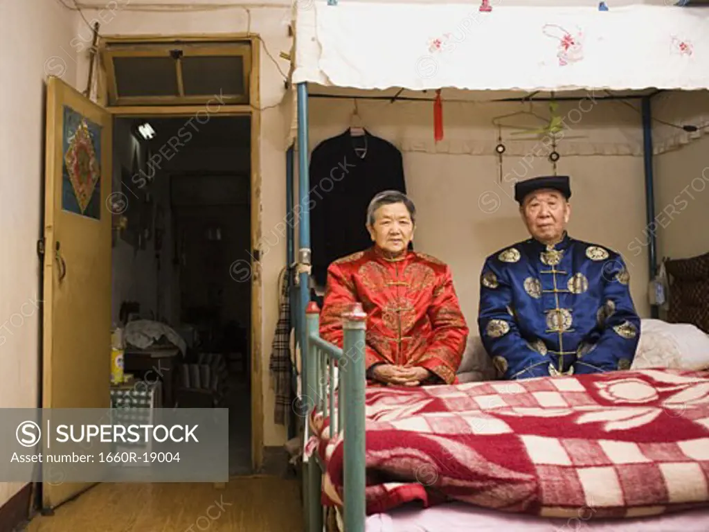 Older couple sitting in room with bed