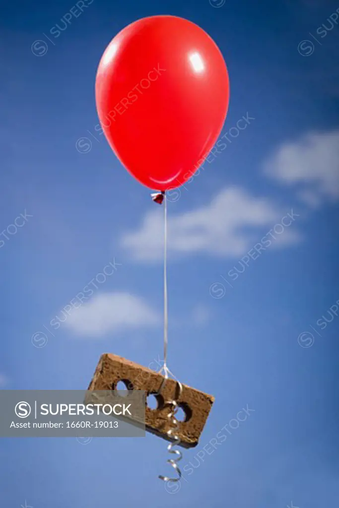 Helium balloon lifting brick outdoors
