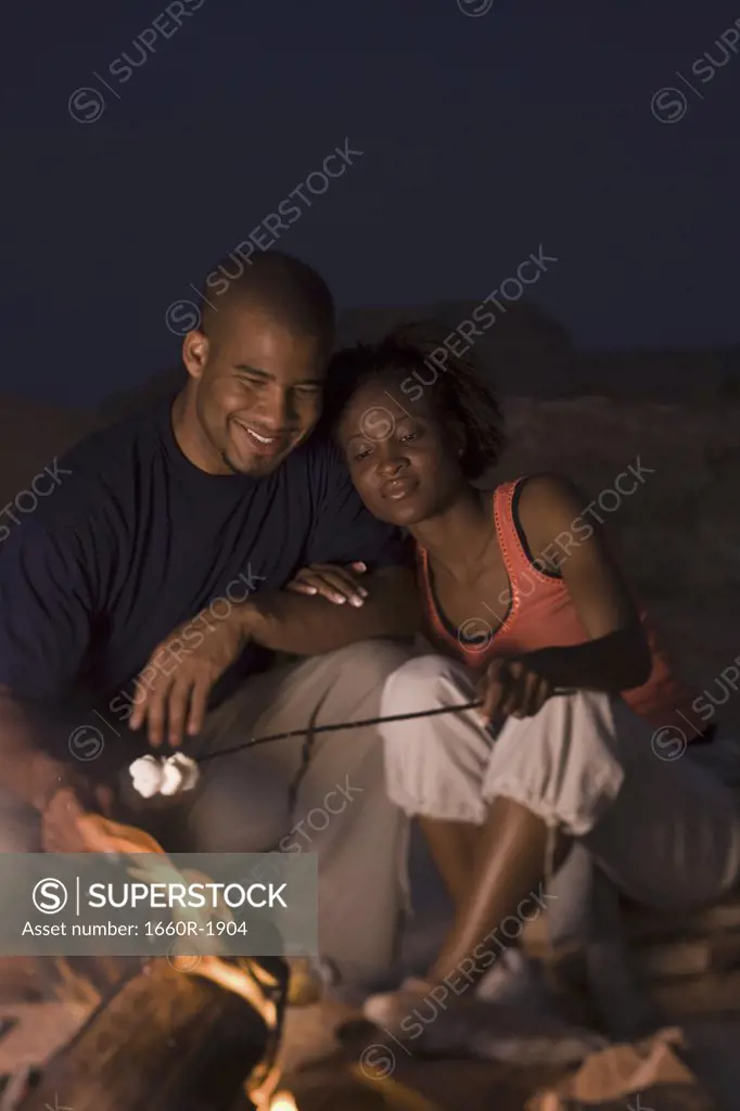 Young couple sitting by a campfire
