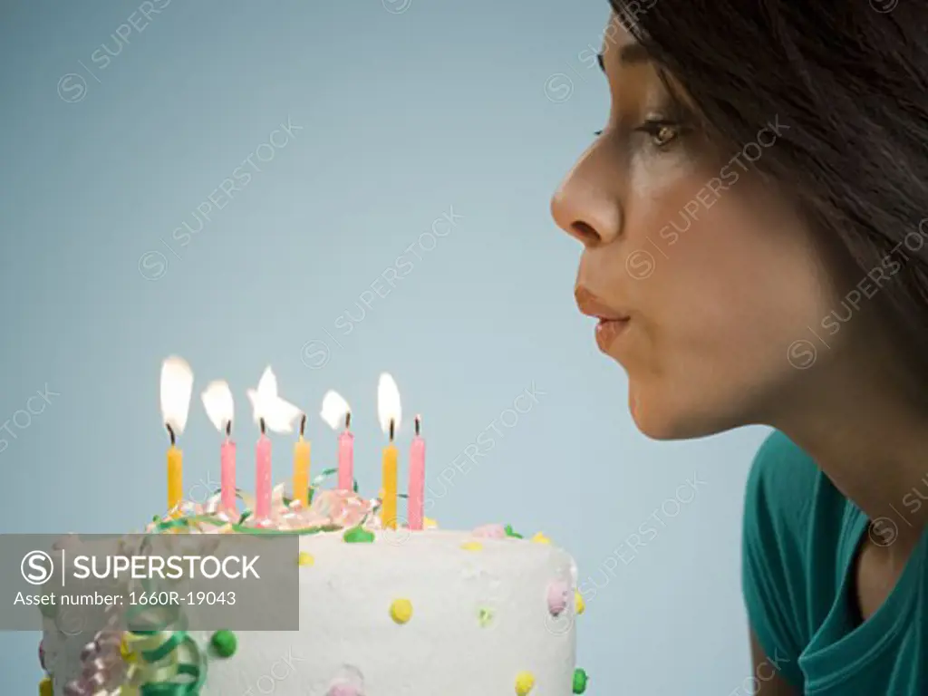 Profile of woman blowing out candles on birthday cake