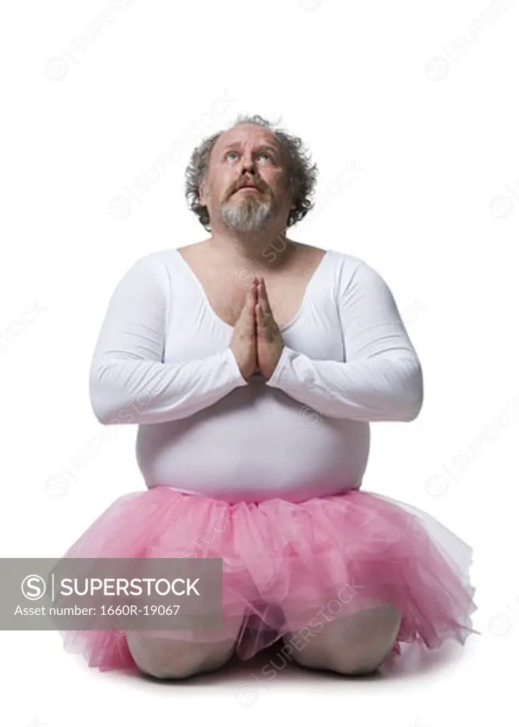 Obese man in tutu kneeling and praying