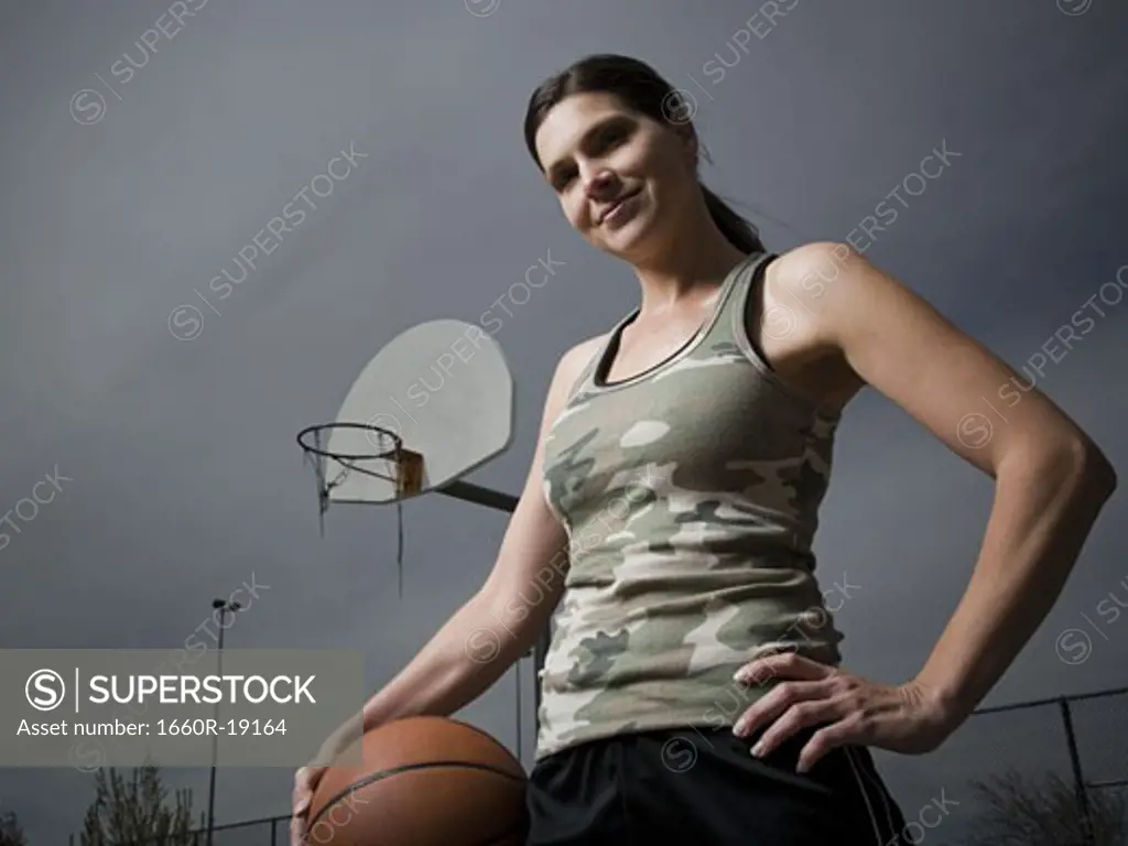 Woman holding basketball with net in background