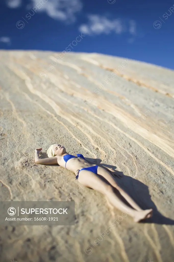High angle view of a young woman sunbathing on a rock