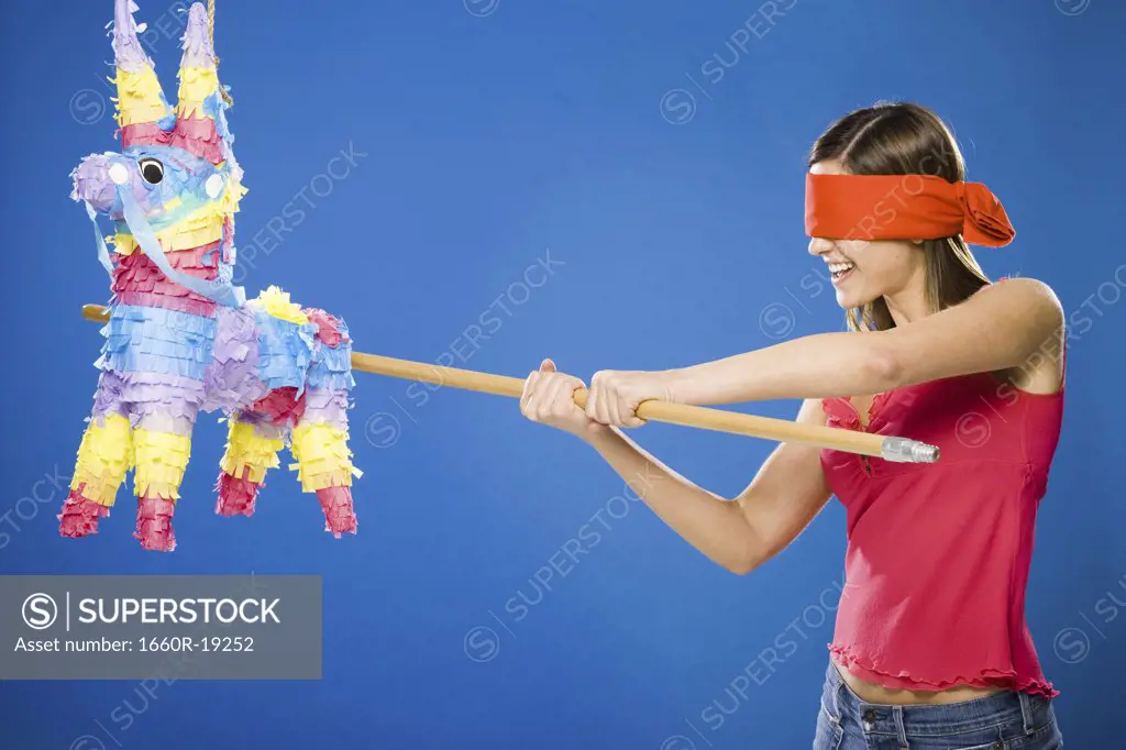 Woman with blindfold hitting pinata with stick