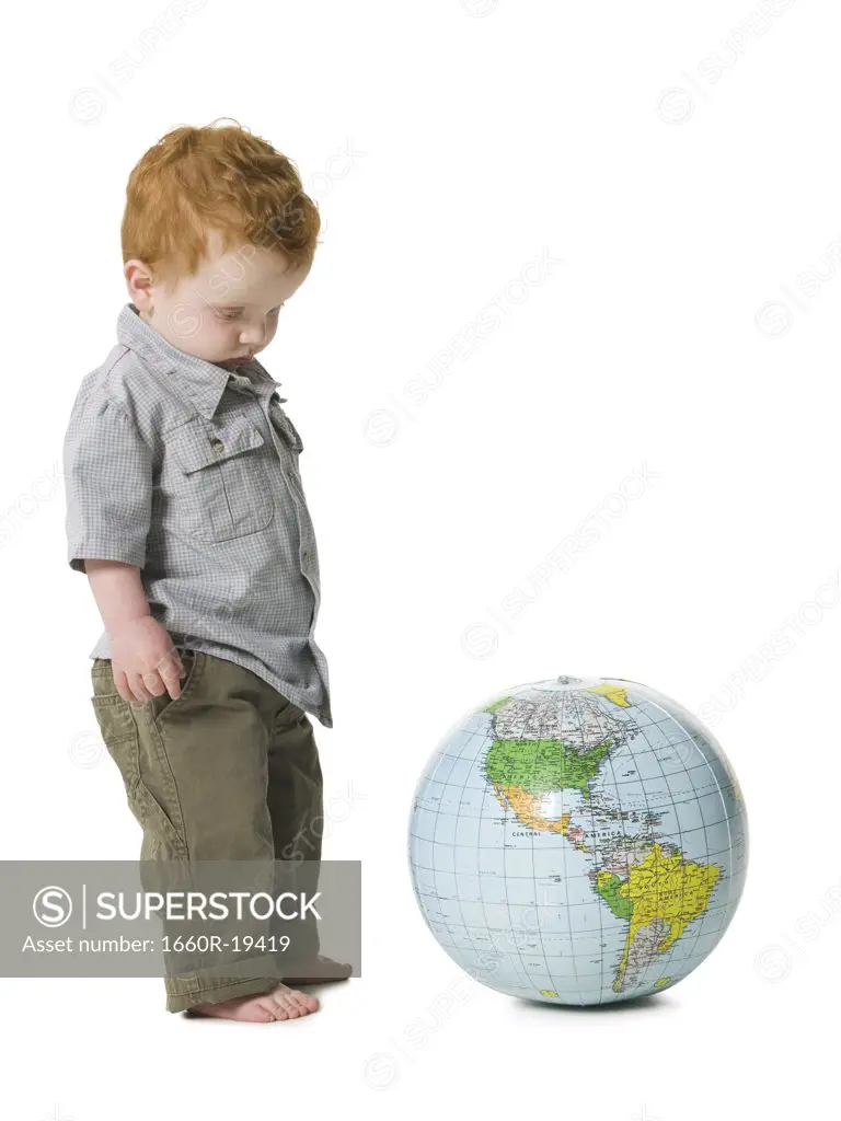 Young boy standing beside globe