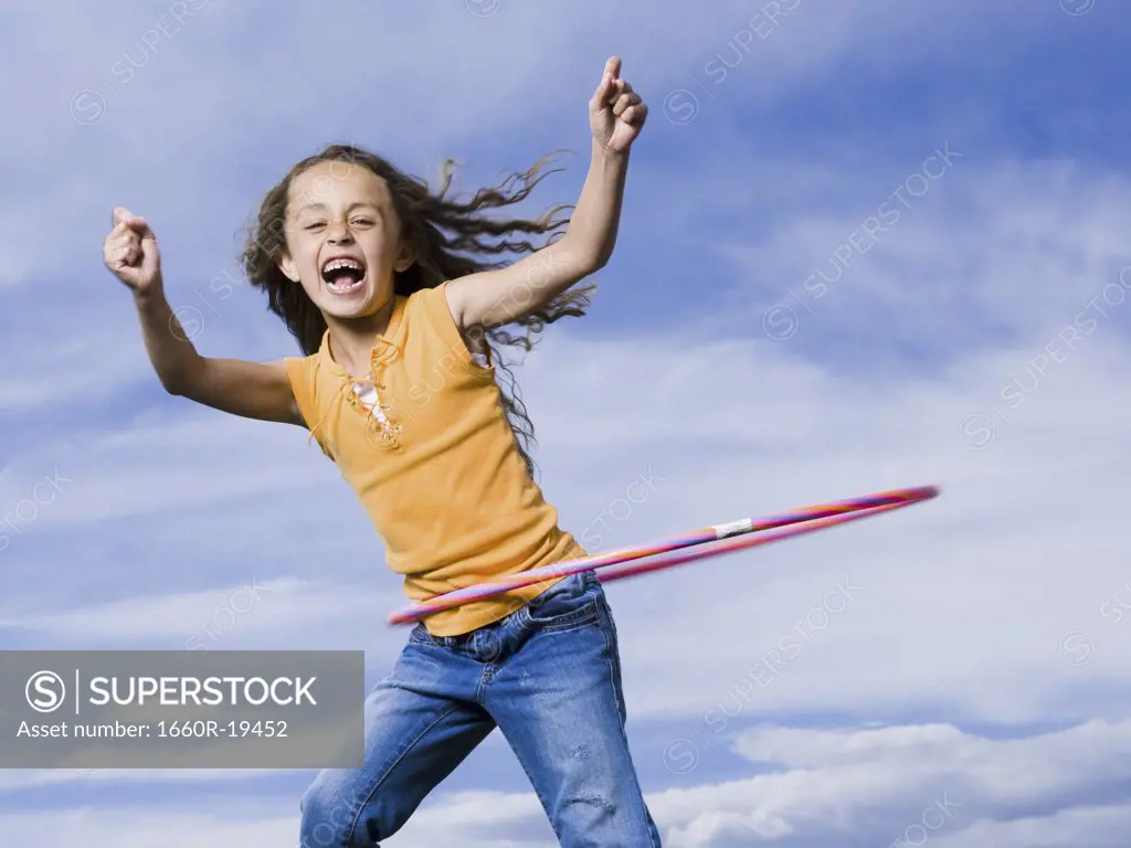 Girl playing with hula hoop outdoors laughing