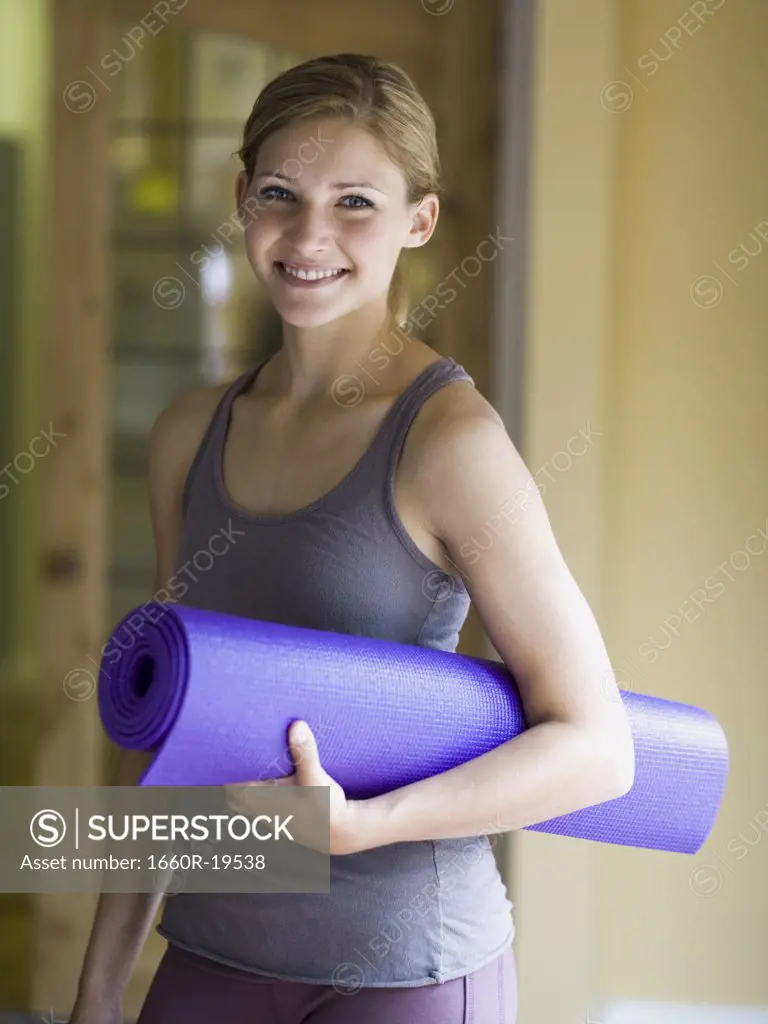 Woman with yoga mat smiling