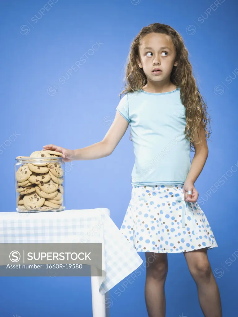 Girl sneaking Chocolate Chip Cookie from cookie jar
