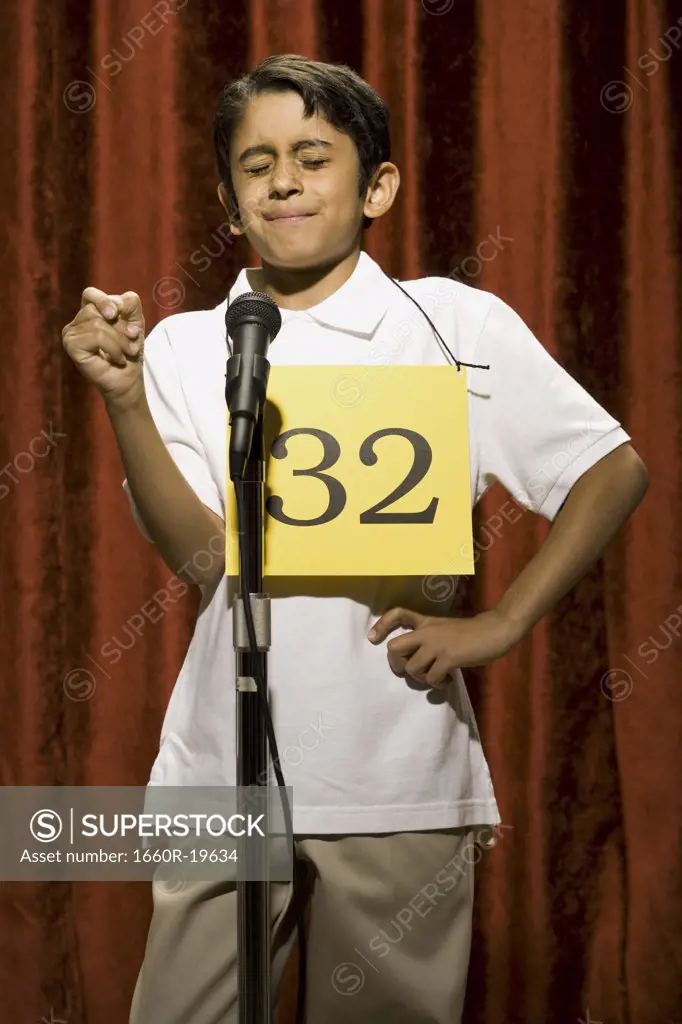 Boy standing at microphone with eyes closed and number on chest