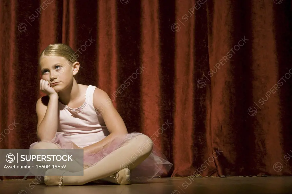 Ballerina girl sitting on stage sulking
