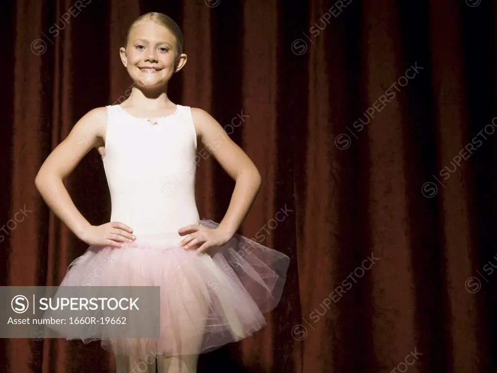 Ballerina girl on stage with hands on hips smiling