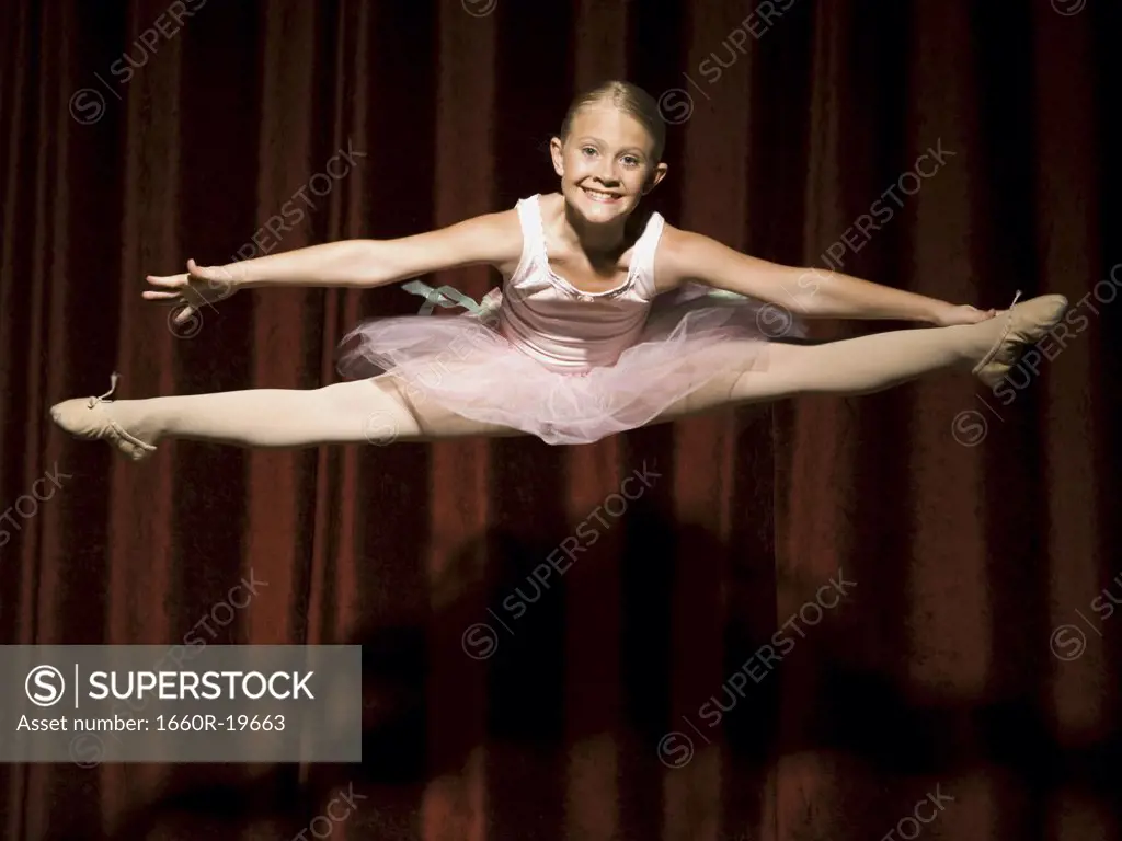 Ballerina girl on stage leaping and smiling