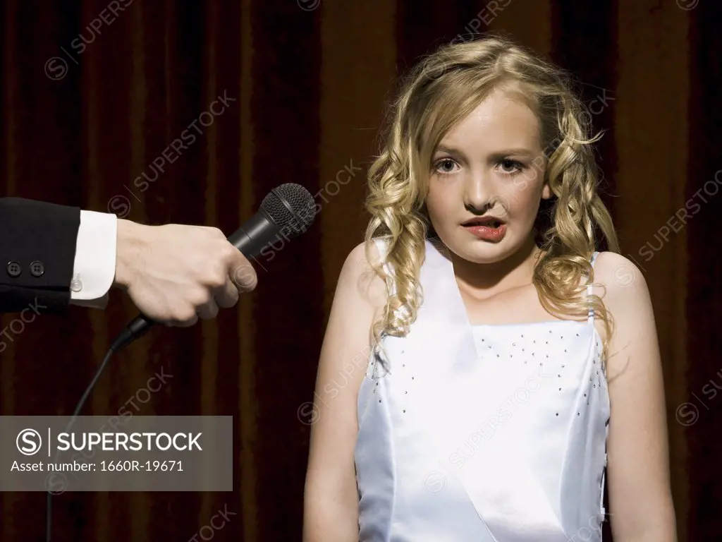 Girl beauty pageant contestant with microphone looking nervous 