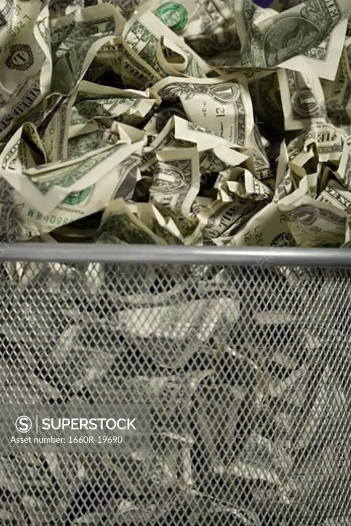 Closeup of crumpled money in waste paper basket