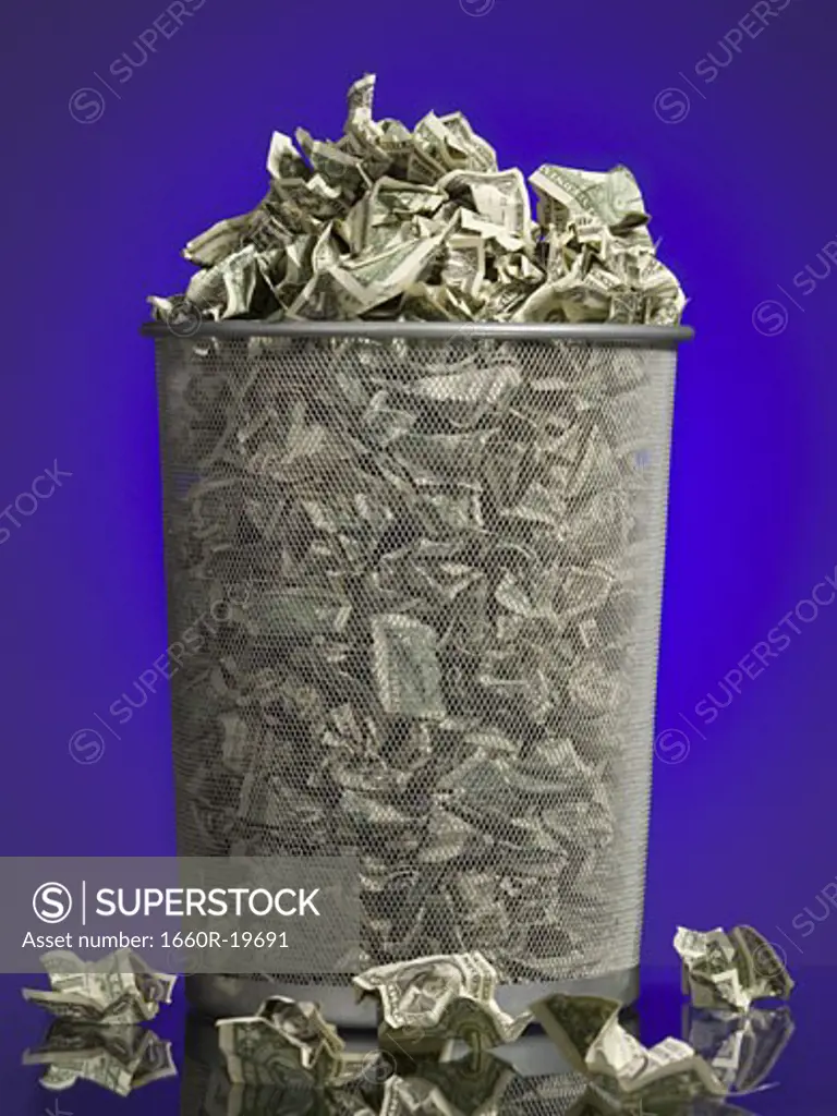 Crumpled money in waste paper basket