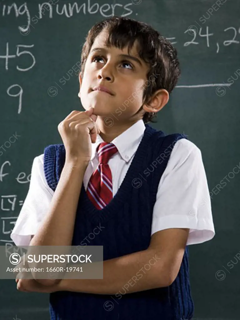 Boy at chalkboard with math formulas thinking