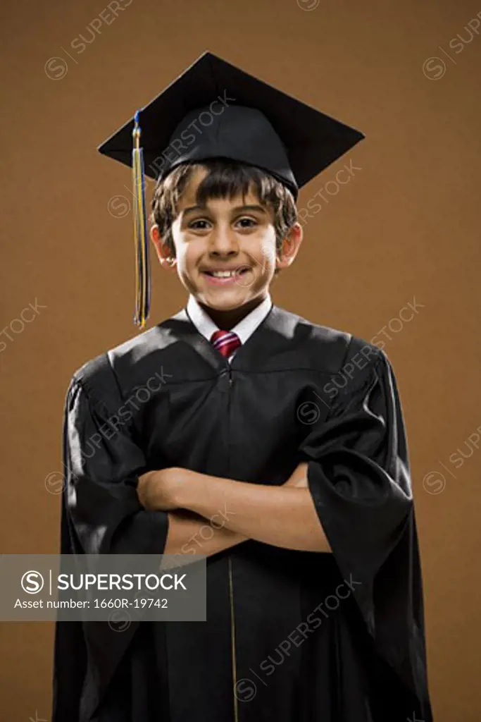 Boy graduate with mortar board smiling with arms crossed