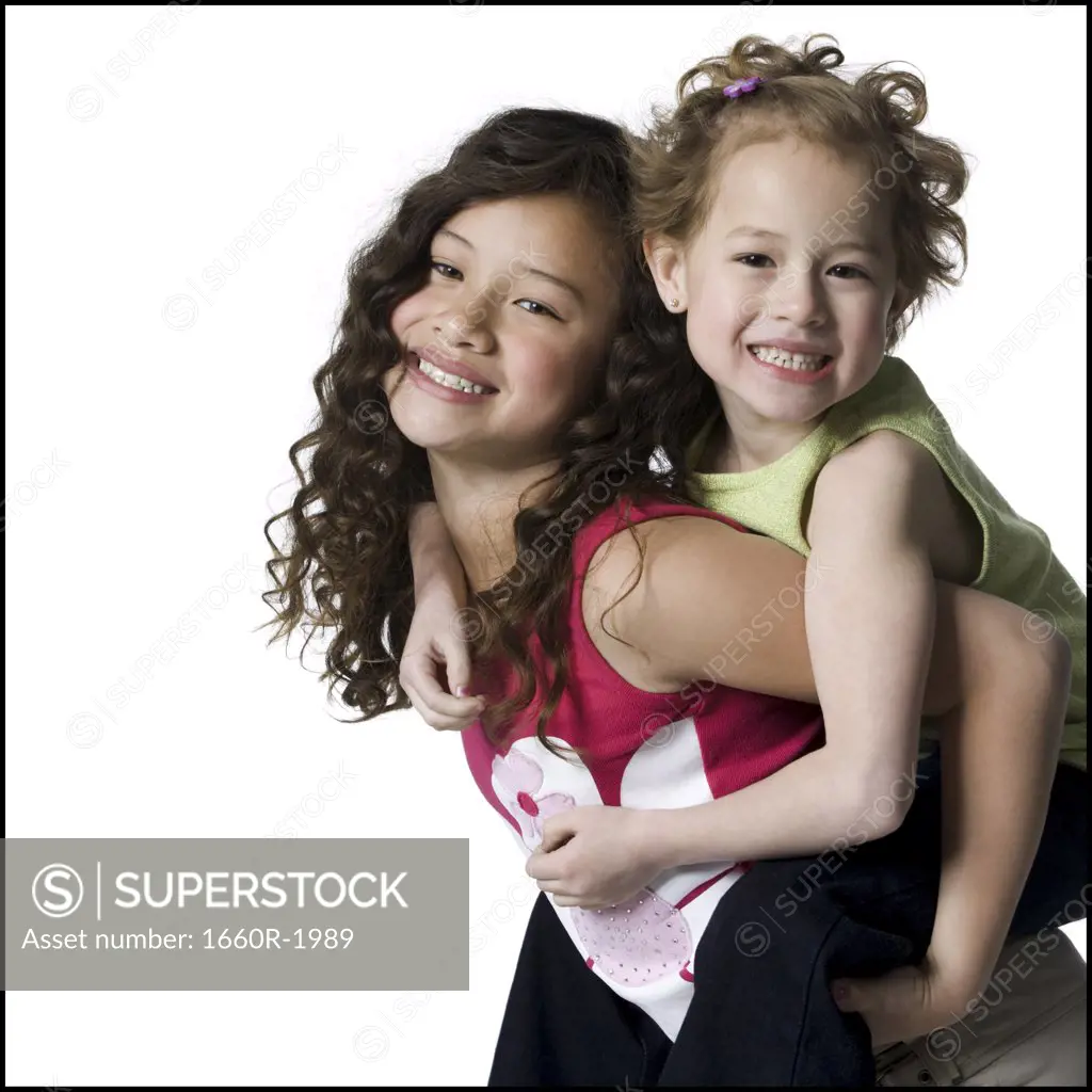 Portrait of a girl riding piggyback on her sister