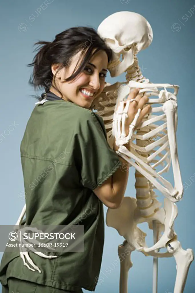 Woman in scrubs dancing with skeleton