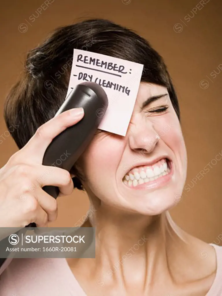 Woman stapling list of things to remember to her forehead and wincing