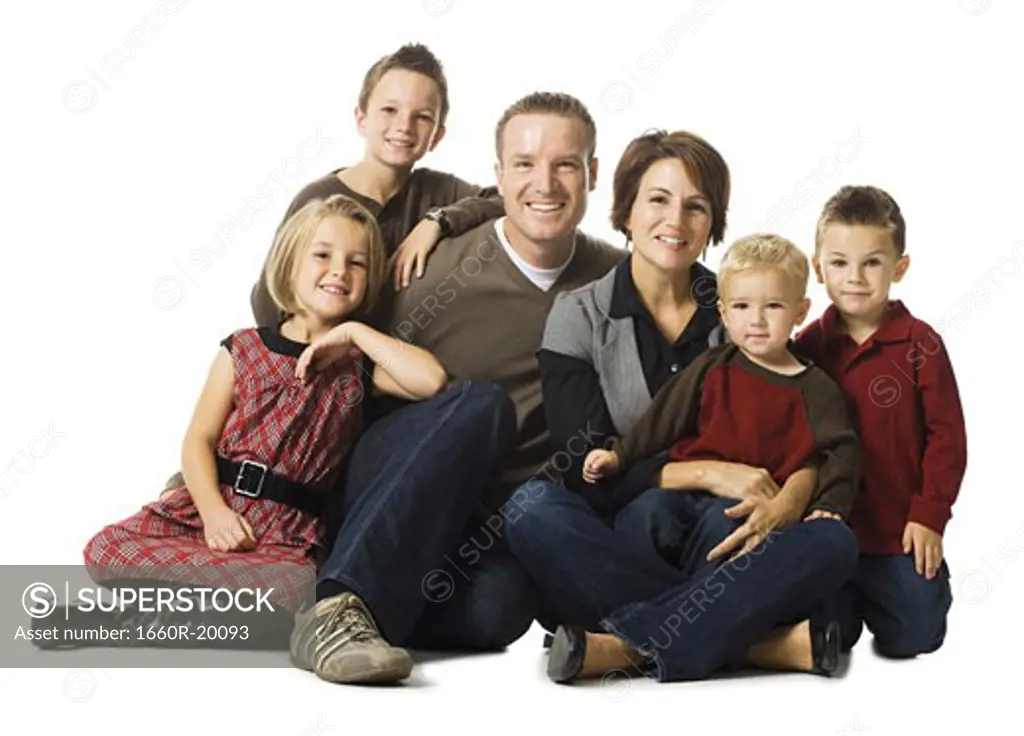 Family of six sitting cross legged posing and smiling