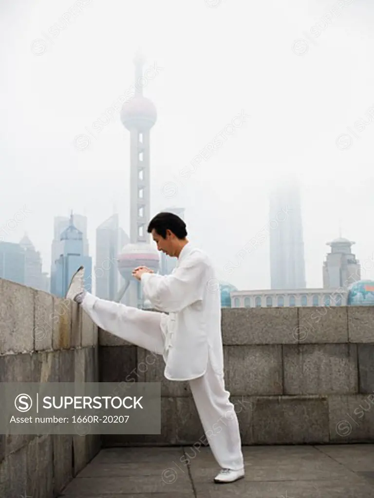 Man doing tai chi outdoors with city skyline in background