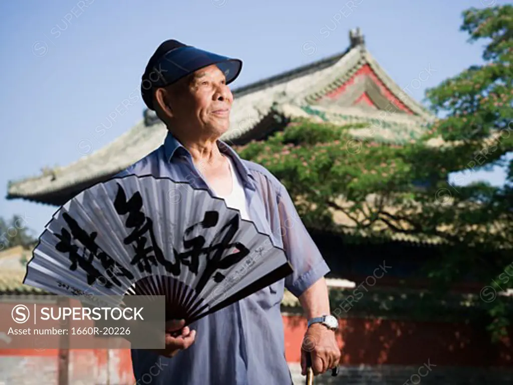 Man holding Chinese fan with pagoda and blue sky in background