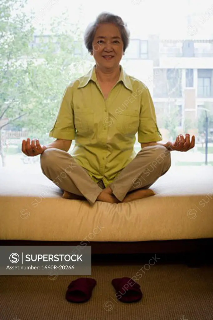 Mature woman sitting cross legged in meditation smiling