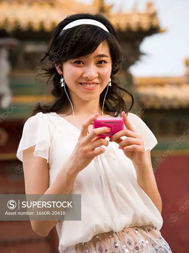 Teenage girl listening to mp3 player and smiling