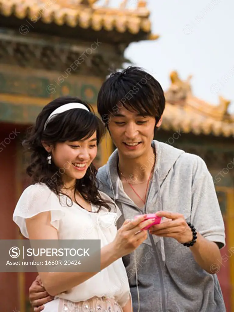 Young couple with mp3 player smiling outdoors