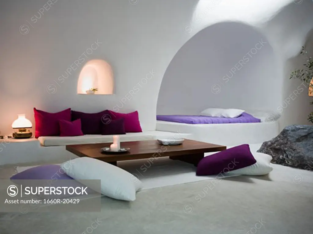 White room with throw pillows sofa and bed with rock inside