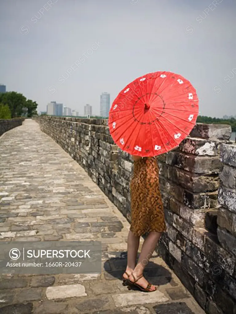 Rear view of woman on stone bridge with parasol