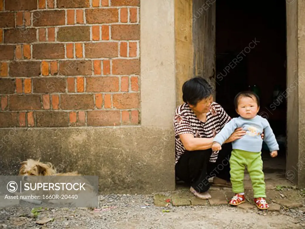 Woman holding baby outdoors with dog