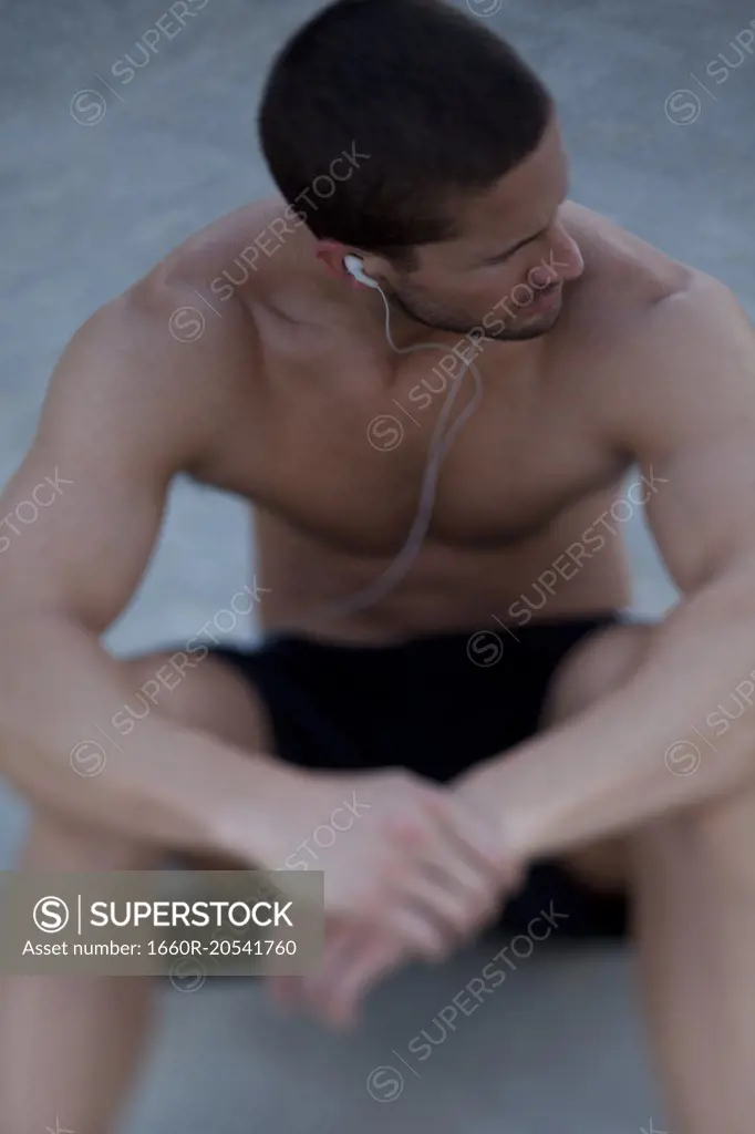 USA, Utah, Orem, Young shirtless man wearing earphones