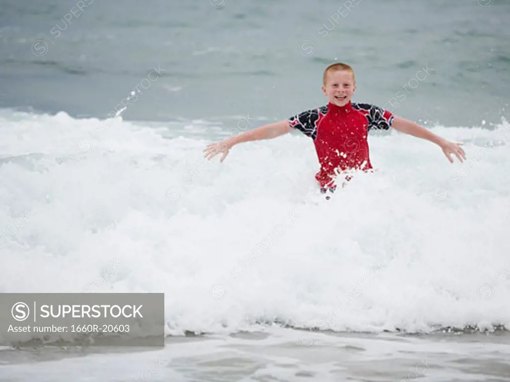 Boy in water with waves smiling
