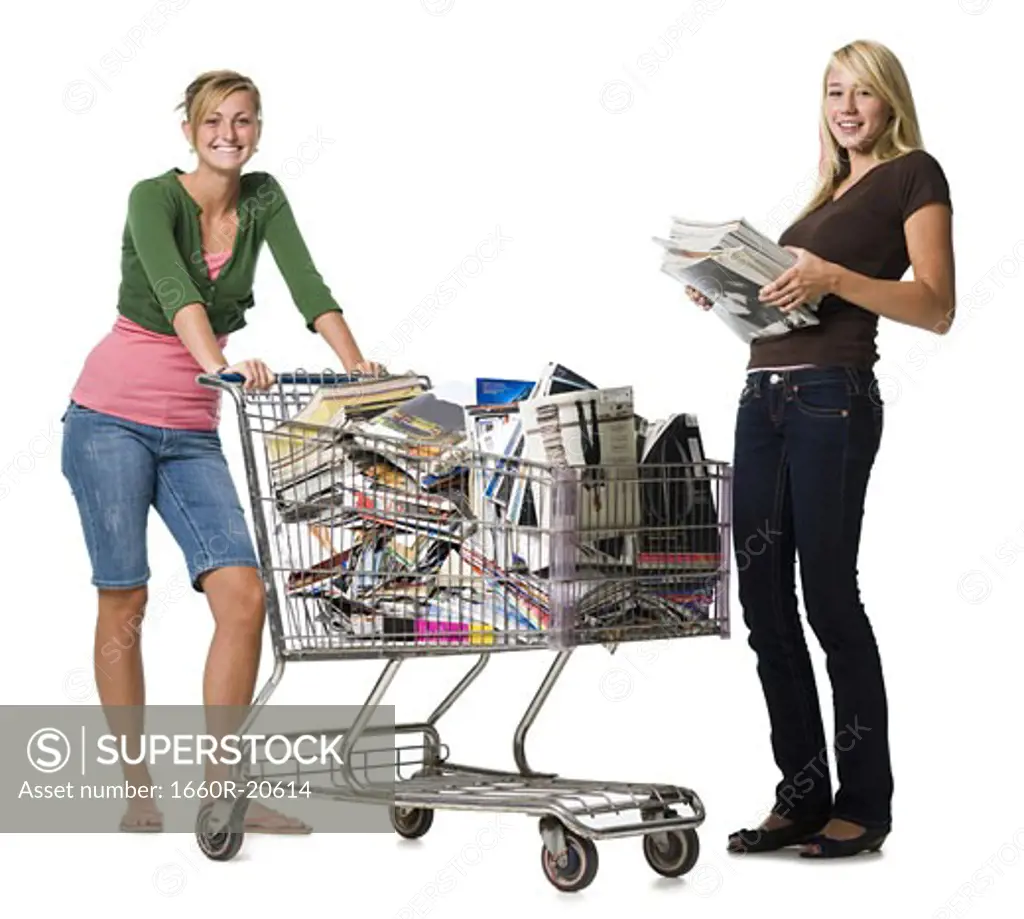 Two teenage girls with shopping cart filled with books and magazines