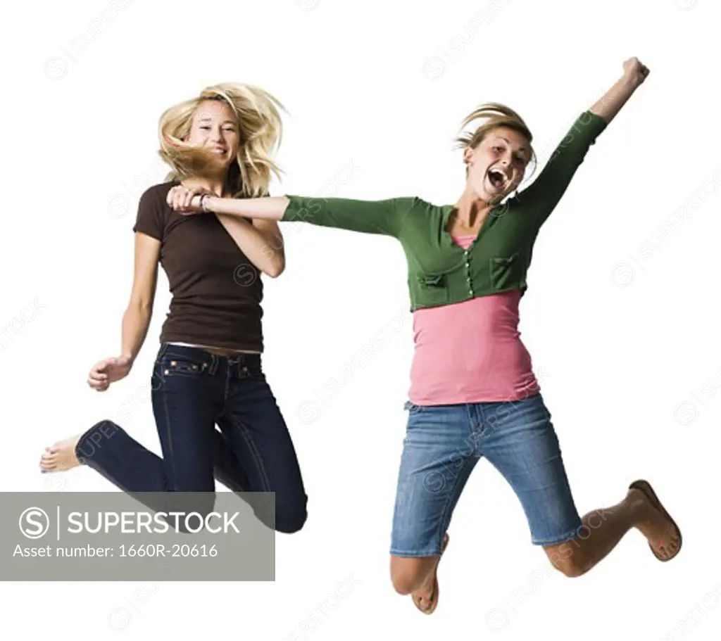 Two teenage girls leaping and smiling