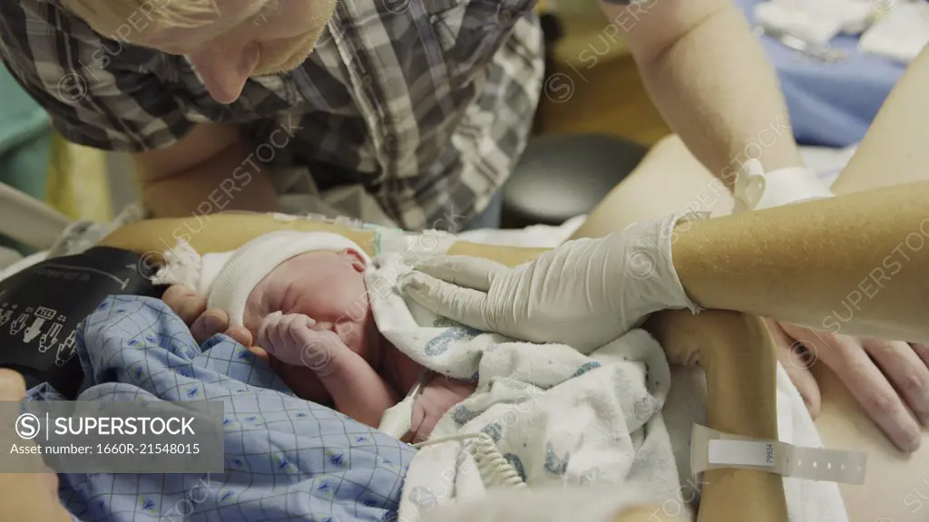 High angle view of new mother and father admiring newborn baby in hospital