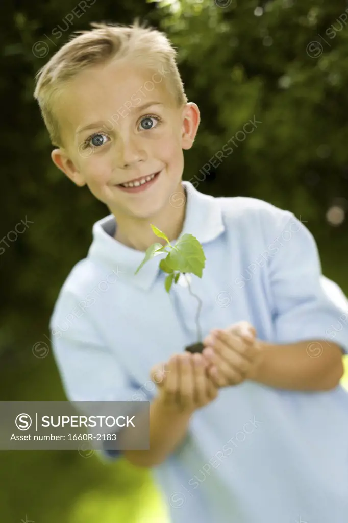 Portrait of a child holding a plant sapling