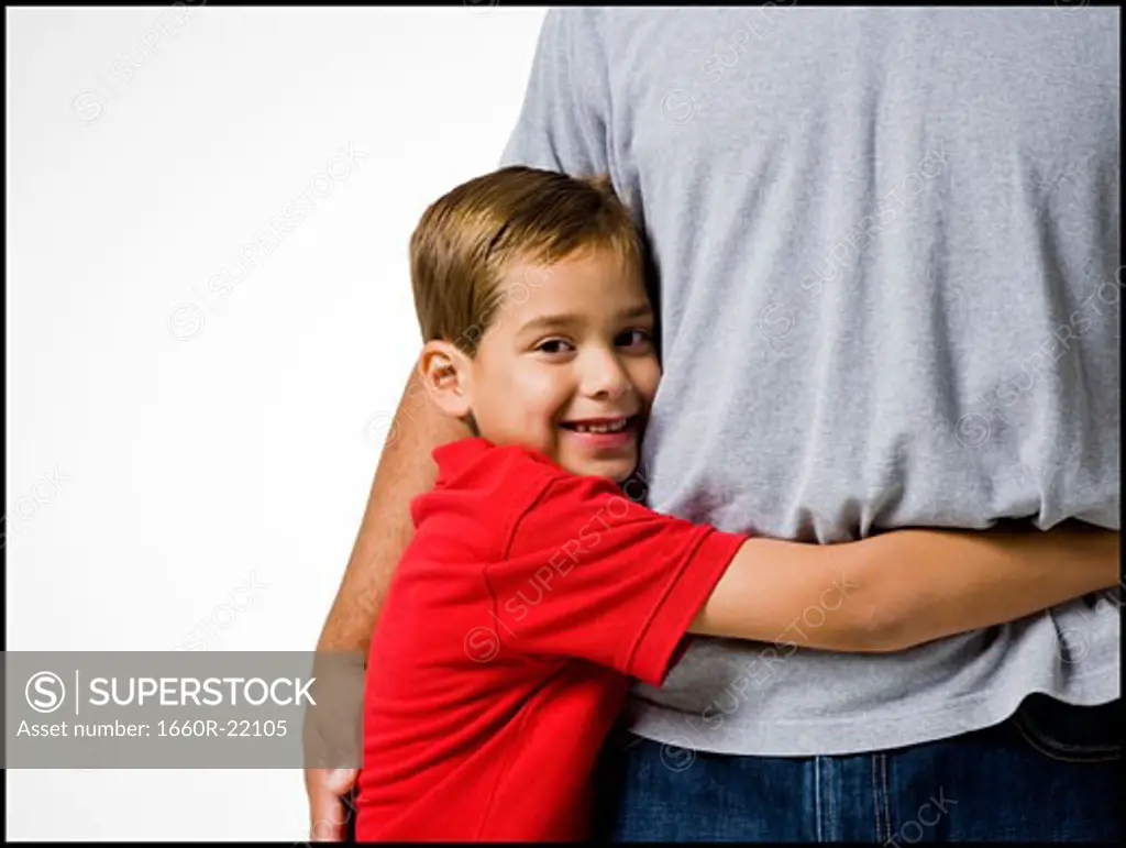 boy in a red shirt hugging a man.